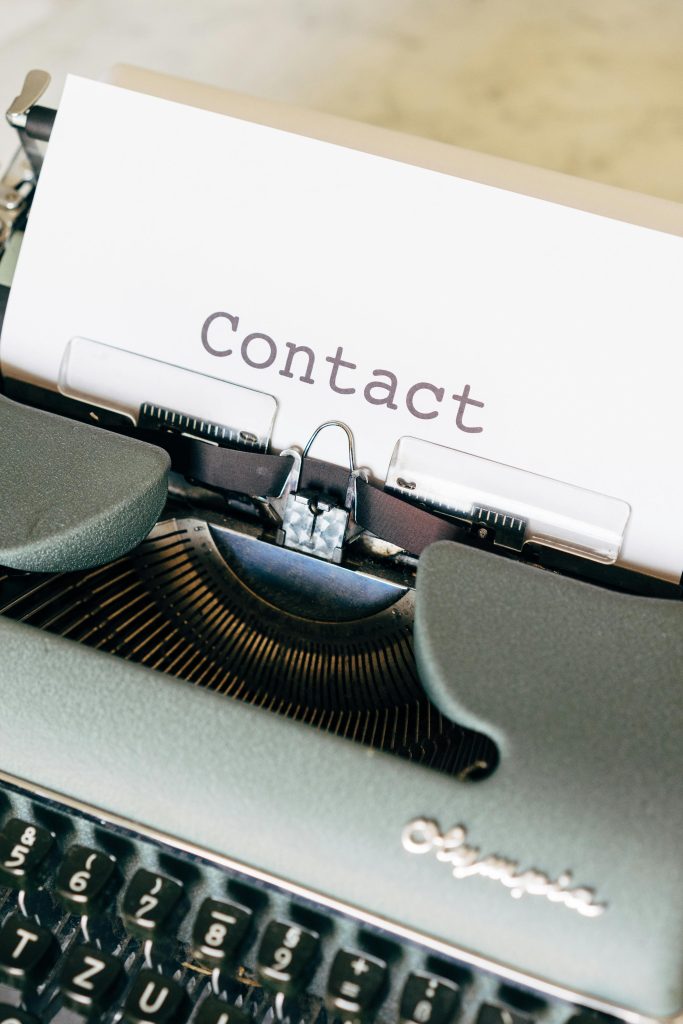 A close-up of a vintage typewriter with paper containing the word 'Contact'.